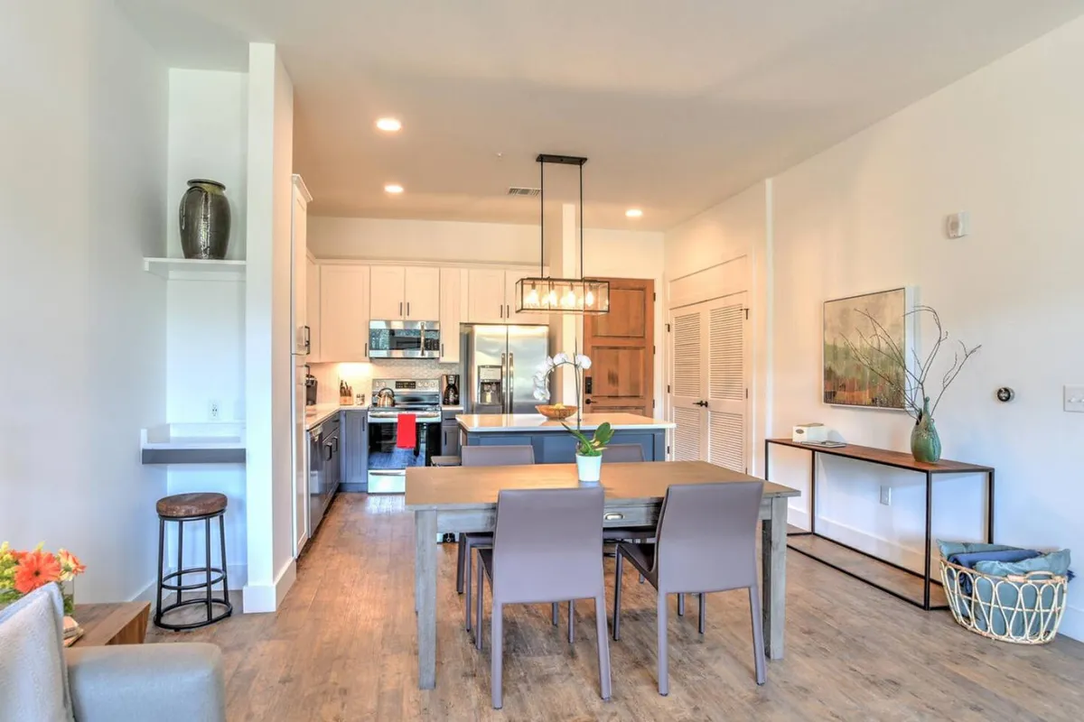 A cozy dining table situated adjacent to the kitchen, complemented by a decorative vase and wall art. The space radiates warmth, perfect for casual breakfasts or intimate dinners.